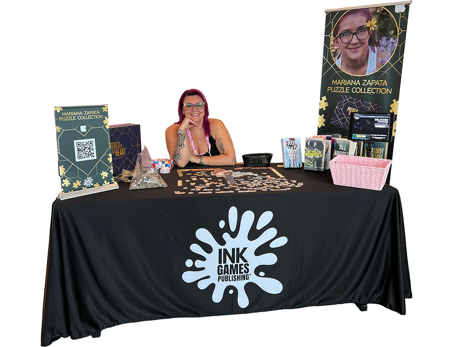 Smiling woman sitting behind table filled with the Mariana Zapata puzzle collection.