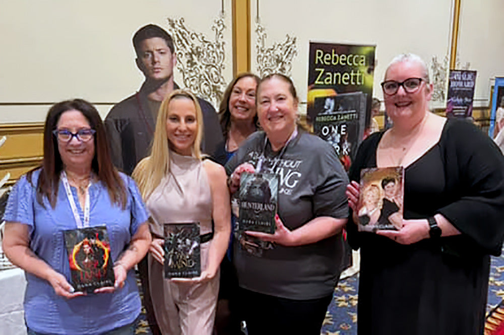 Group of people holding books with a focus on a book signing event.