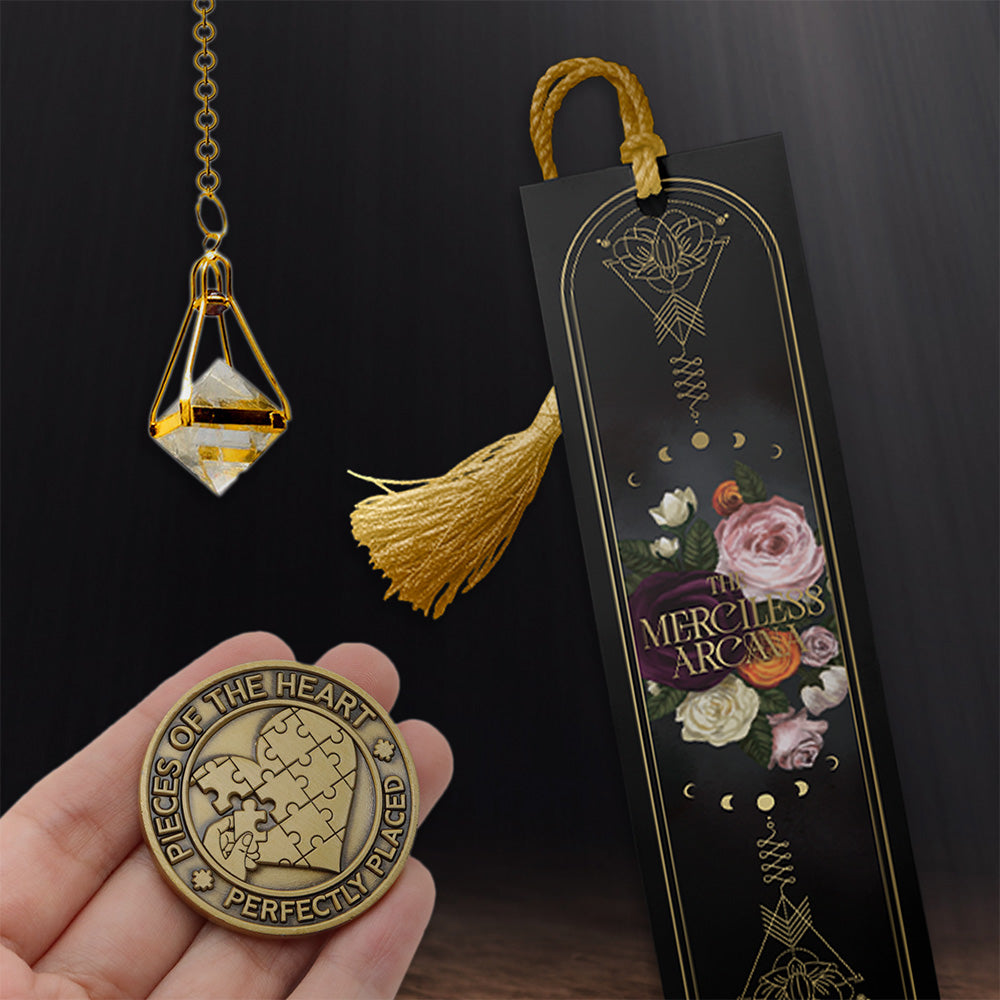 Gold pendant, bookmark, and coin held by a hand on a dark background.